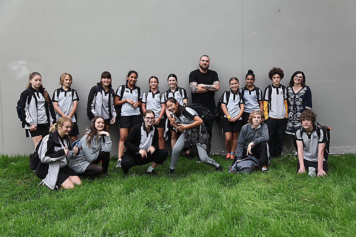 students standing on green grass while artist Thomas Jackson leans against a wall